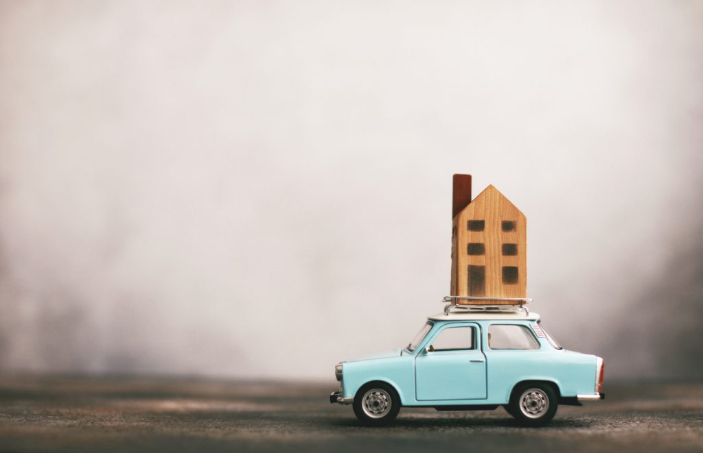Little blue car with house on roof rack. Relocation concept
